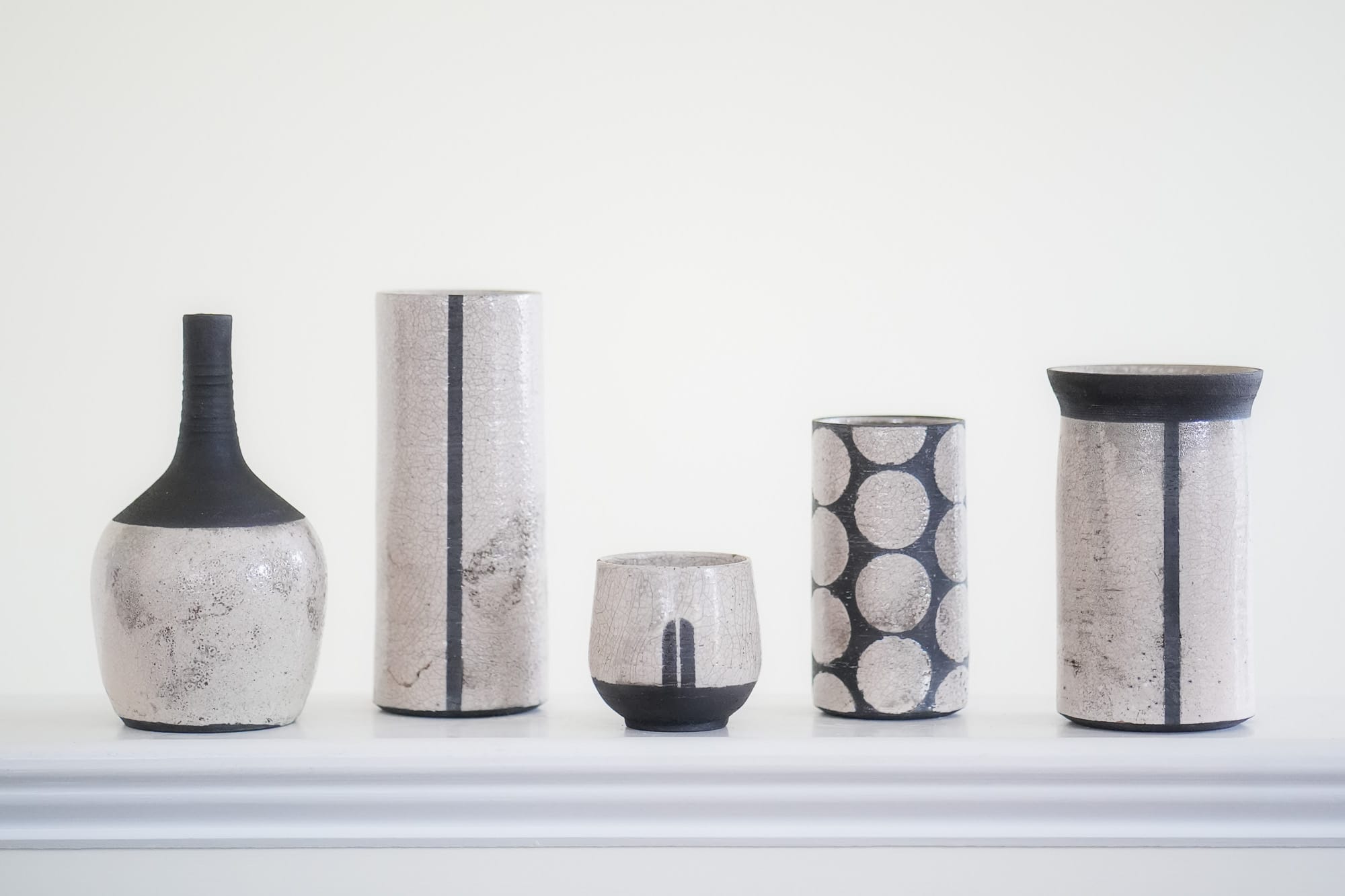 photo of five black and white raku-fired pottery vases in various shapes and sizes